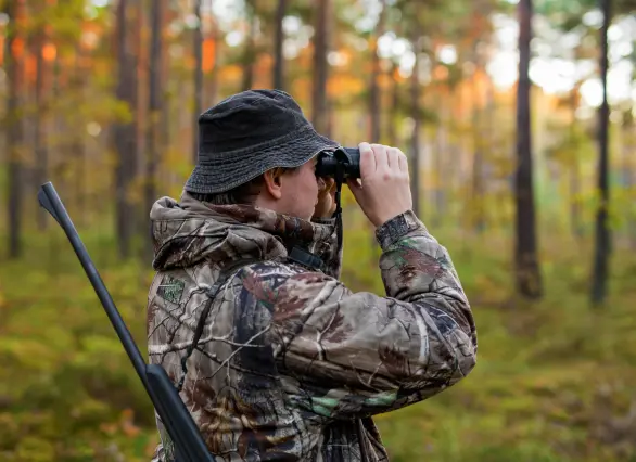 a hunter using a scope in a jungle