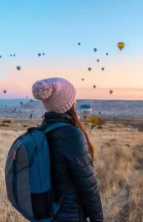 a traveller seeing the sky that is full with air balloons